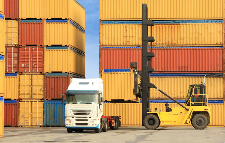 forklift loading containers on white truck in horbor